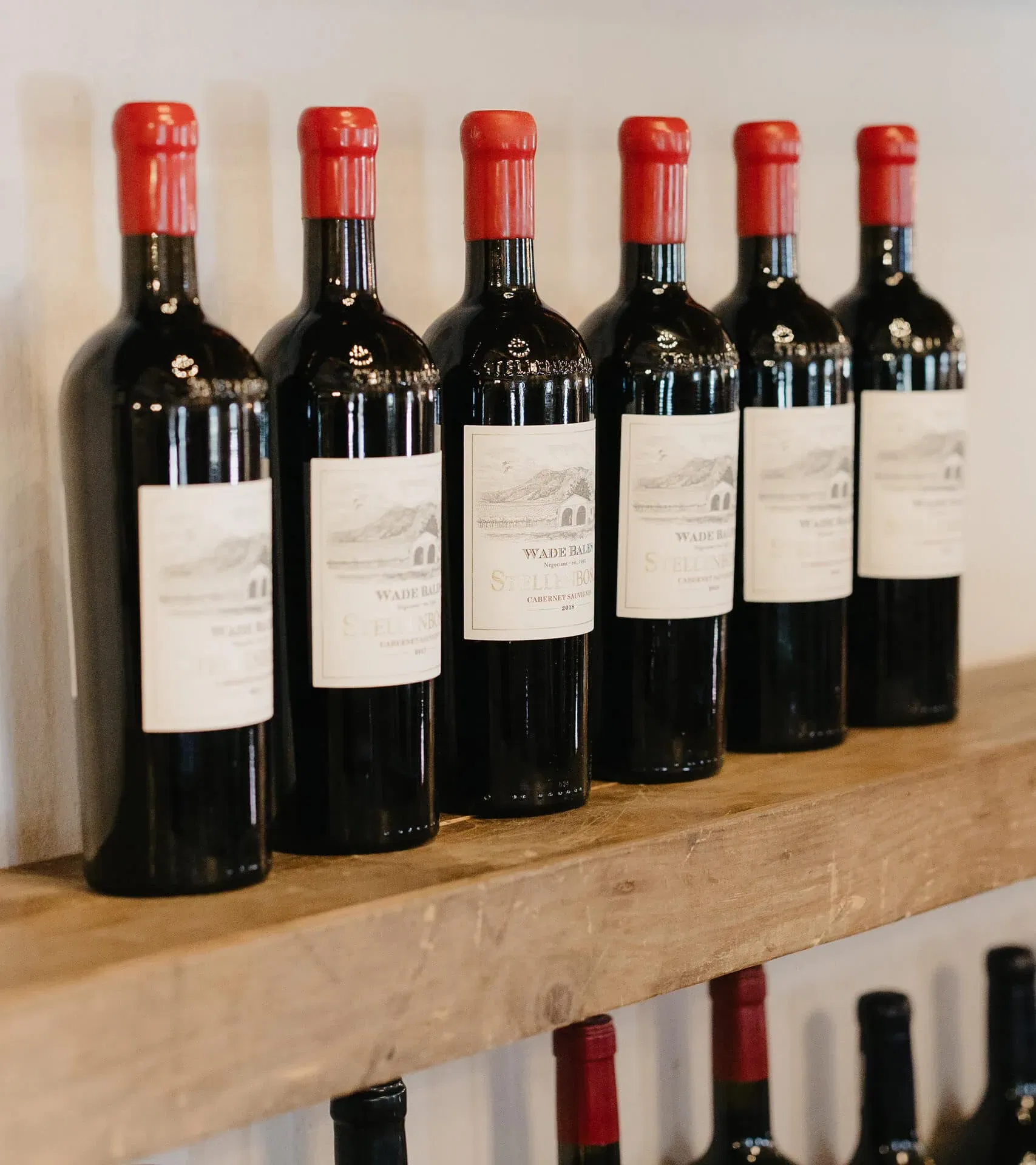 Bottles Of Stellenbosch Cabernet Sauvignon Lined On A Wooden Shelf.