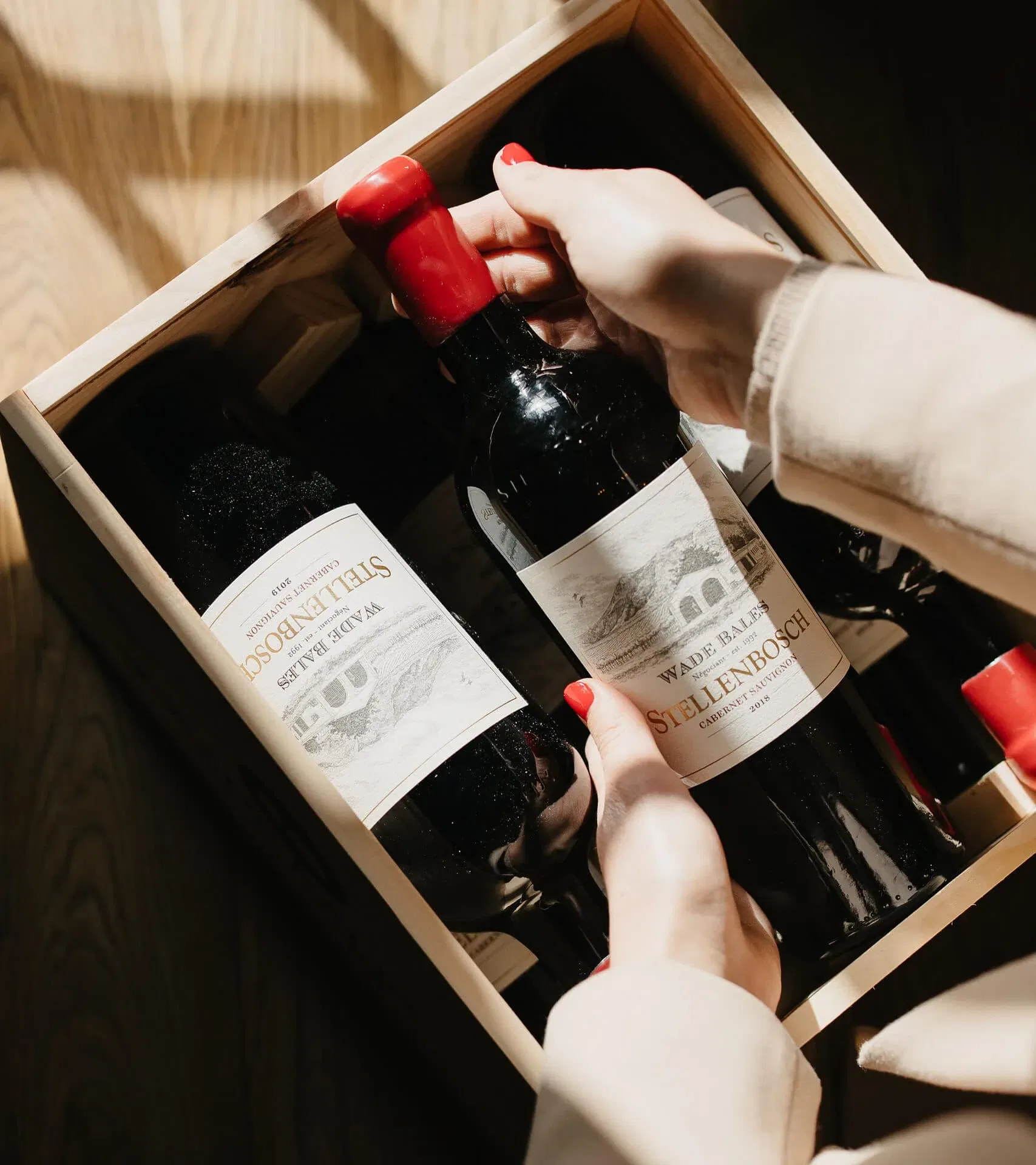 Hand selecting a bottle of Stellenbosch Cabernet Sauvignon at Simon Wine Emporium.