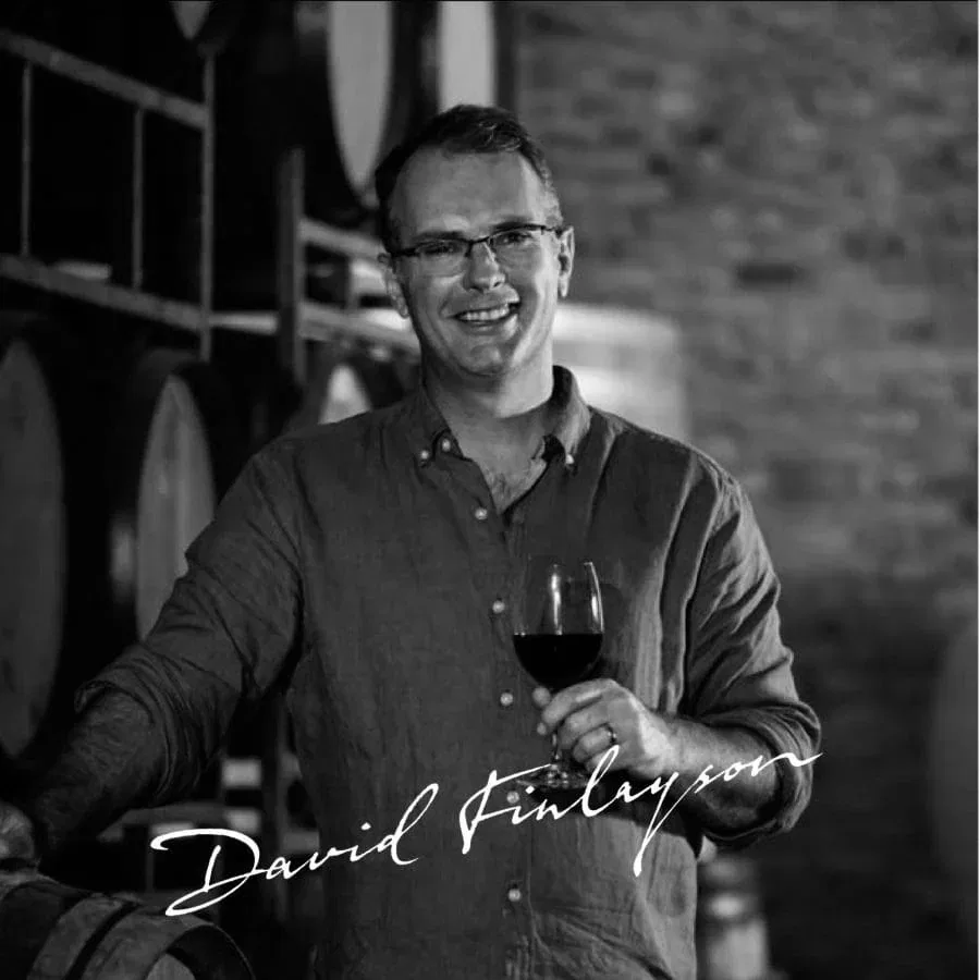 Smiling winemaker holding a glass of Stellenbosch wine.