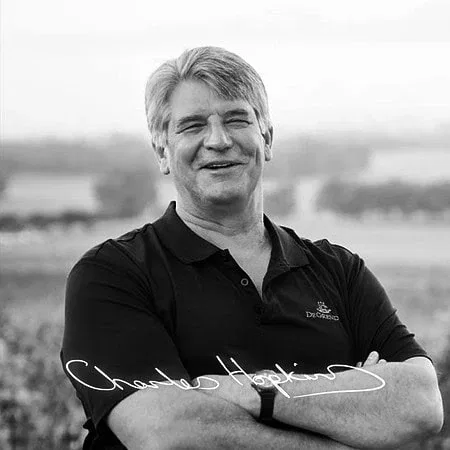 Smiling Winemaker In Stellenbosch Vineyard, Showcasing South African Wine Expertise.