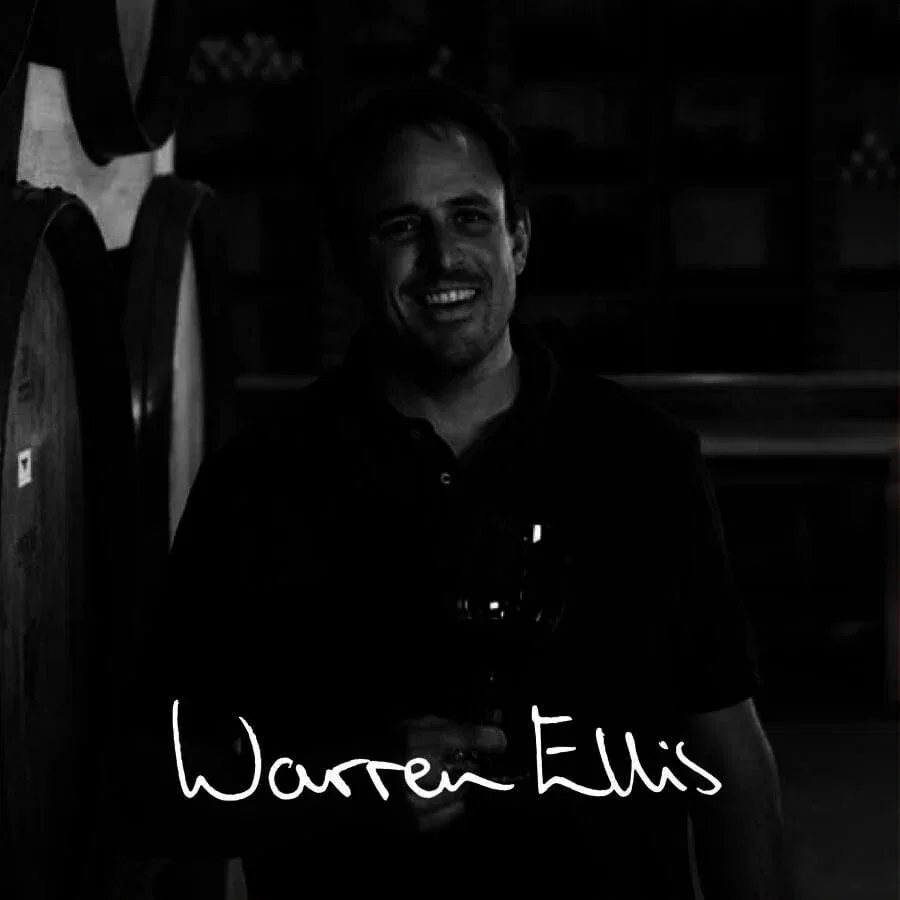 Smiling winemaker holding a glass of Stellenbosch wine.