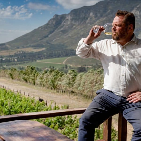 Andre Morgenthal enjoys wine amidst a vineyard with mountains